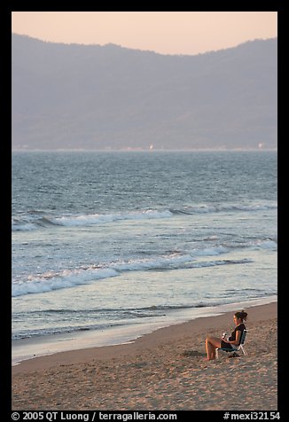 Woman sitting on the beach looking at the sunset, Nuevo Vallarta, Nayarit. Jalisco, Mexico