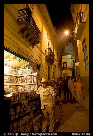 Man at a Newstand booth in a narrow callejone at night. Guanajuato, Mexico