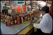 Man sitting at a booth offering a large variety of bottled chili. Guanajuato, Mexico (color)