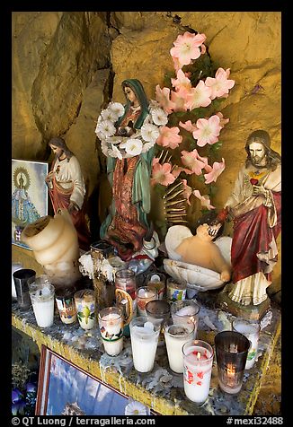 Religious figures and candles in roadside chapel. Mexico