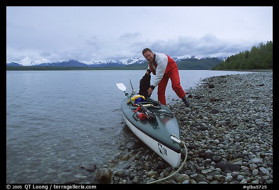 Kayaker loading gear into a double kayak. Glacier Bay National Park, Alaska