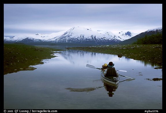 Kayaker paddles in  a shallow tidal channel into Scidmore Bay. Glacier Bay National Park, Alaska (color)
