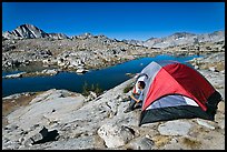 Man sitting in tent above lake, Dusy Basin. Kings Canyon National Park, California, USA.