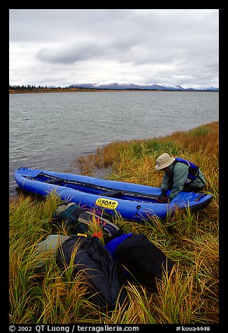 Canoeist unloading the canoe on a grassy riverbank. Kobuk Valley National Park, Alaska (color)