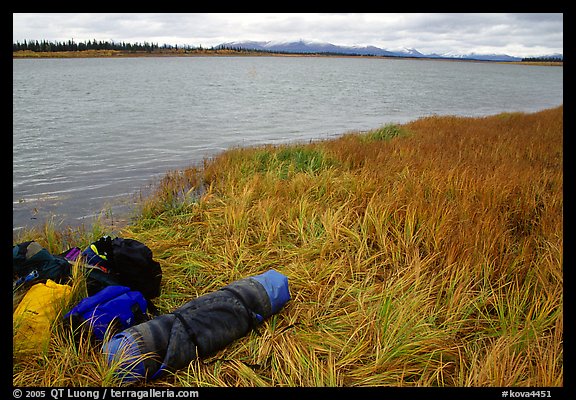 Gear and folded  canoe on a grassy riverbank of the Kobuk River. Kobuk Valley National Park, Alaska
