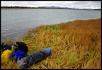 Gear and folded  canoe on a grassy riverbank of the Kobuk River. Kobuk Valley National Park, Alaska ( color)