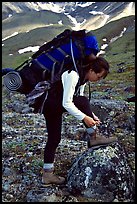 Woman backpacker with a large backpack tying up her shoelaces. Lake Clark National Park, Alaska ( color)