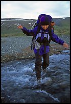 Backpacker balancing herself while crossing a stream. Lake Clark National Park, Alaska (color)