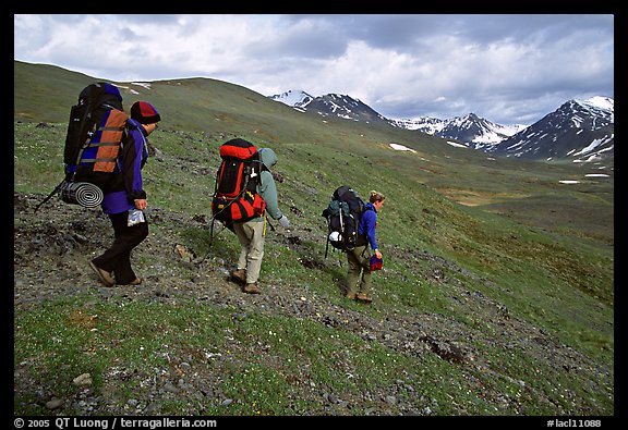 Backpackers with big packs going down a slope. Lake Clark National Park, Alaska
