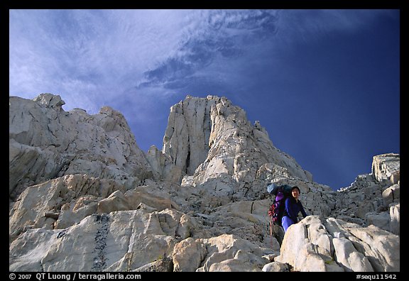 Looking up to woman scrambling on rocks on the East face of Mt Whitney. Sequoia National Park, California