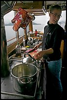 Chef cooking aboard small boat. Glacier Bay National Park, Alaska, USA.