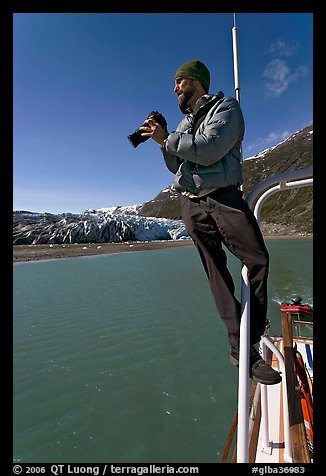 Photographer perched on boat in Reid Inlet. Glacier Bay National Park (color)