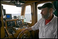 Captain steering boat with navigation instruments. Glacier Bay National Park, Alaska, USA.