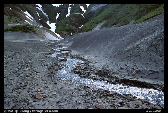 Stream flows from verdant hills into  barren valley floor. Katmai National Park (color)