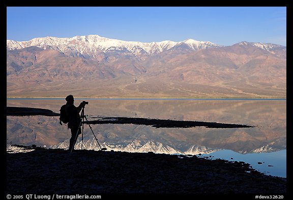 Photographer and Panamint range reflected in a seasonal lake, early morning. Death Valley National Park, California, USA.
