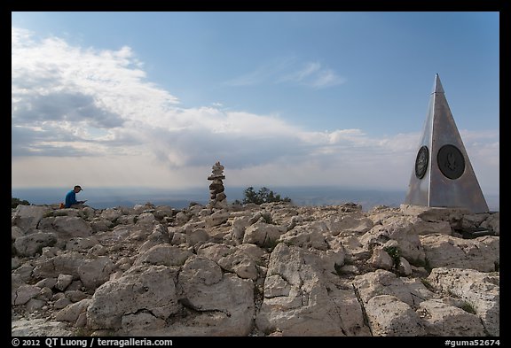 Hiker sitting on Guadalupe Peak summit with cairn and monument. Guadalupe Mountains National Park (color)