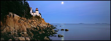 Dusk seascape with lightouse, moon, and reflection. Acadia National Park, Maine, USA.