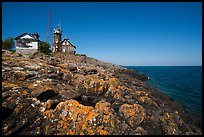 Lichen-covered rocks and Lighthouse, Passage Island. Isle Royale National Park, Michigan, USA.