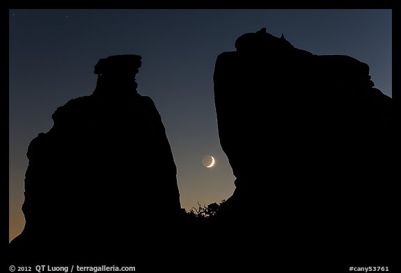 Crescent moon framed by Dollhouse spires. Canyonlands National Park, Utah, USA.