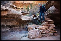Hiker stepping down on primitive stairs, Maze District. Canyonlands National Park, Utah, USA.
