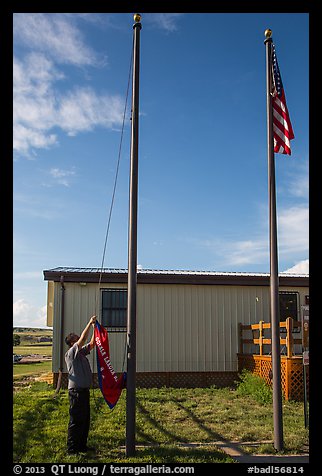 Ranger lowering Ogala Lakota flag, White River Visitor Center. Badlands National Park (color)