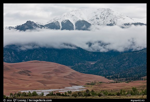 Dunes and Medano creek below snowy mountains. Great Sand Dunes National Park, Colorado, USA.