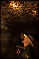 Ranger pointing flashlight at boxwork. Wind Cave National Park, South Dakota, USA. (color)