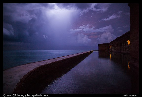 Fort Jefferson seawall at night with sky lit by thunderstorm. Dry Tortugas National Park, Florida, USA.