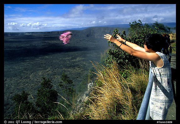 Woman throws flowers into Kilauea caldera as offering to Pele. Hawaii Volcanoes National Park, Hawaii, USA.