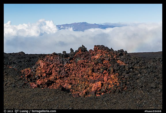 Black of colorful lava on Mauna Loa, Mauna Kea emerging from Saddle clouds. Hawaii Volcanoes National Park, Hawaii, USA.
