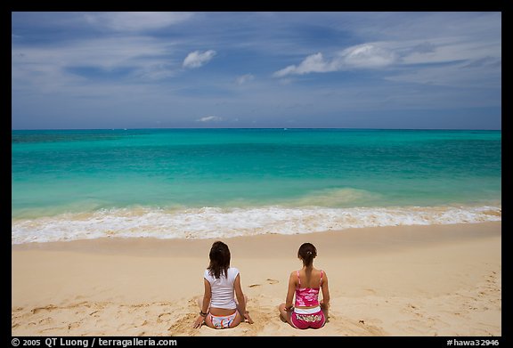 Young women facing ocean in meditative pose on Waimanalo Beach. Oahu island, Hawaii, USA