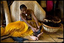 Fiji woman tying together leaves with her feet. Polynesian Cultural Center, Oahu island, Hawaii, USA (color)