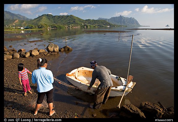 Fisherman with family and small baot, Kaneohe Bay, morning. Oahu island, Hawaii, USA
