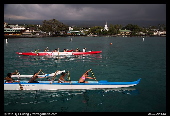 Outrigger canoes and town under storm sky, Kailua-Kona. Hawaii, USA