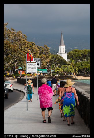 Beachgoers walking past ironman triathlon sign, Kailua-Kona. Hawaii, USA (color)