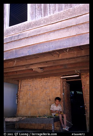 Boy at the entrance of traditional hut, Ban Xang Hai. Laos (color)