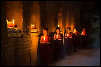 Buddhist novices in temple illuminated with candles. Bagan, Myanmar