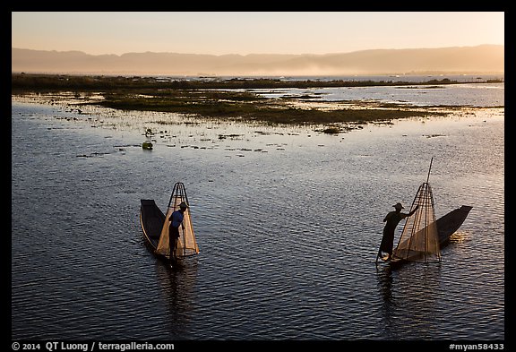 Intha fishermen row with backlit conical nets. Inle Lake, Myanmar (color)