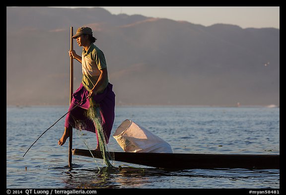 Fisherman pulling up net while leg-rowing. Inle Lake, Myanmar (color)