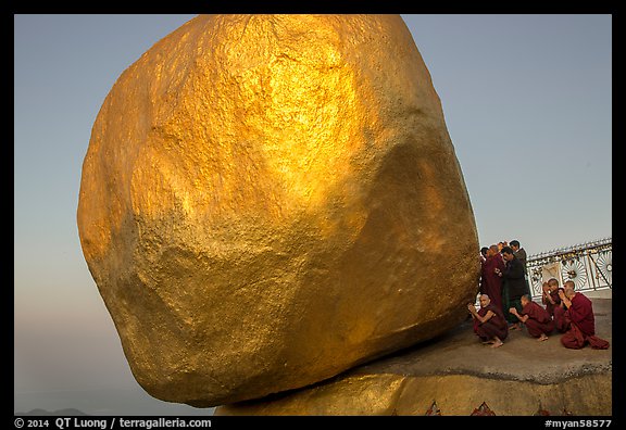 Monks praying at the Golden Rock balancing boulder. Kyaiktiyo, Myanmar (color)