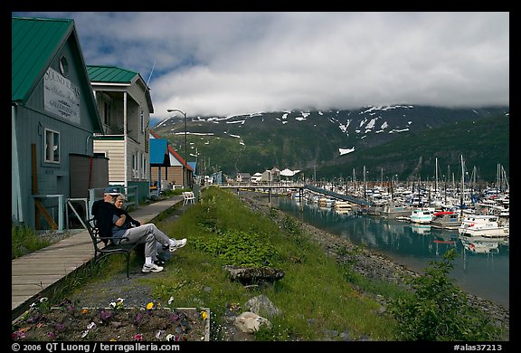 Couple sitting on bench by the harbor. Whittier, Alaska, USA