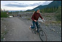Woman on mountain bike with bridge behind. McCarthy, Alaska, USA ( color)
