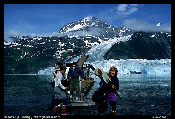 Kayakers unloading kayak from water taxi boat at Black Sand Beach. Prince William Sound, Alaska, USA (color)