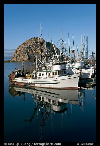Fishing boats reflected in harbor,  and Morro Rock, early morning. Morro Bay, USA (color)