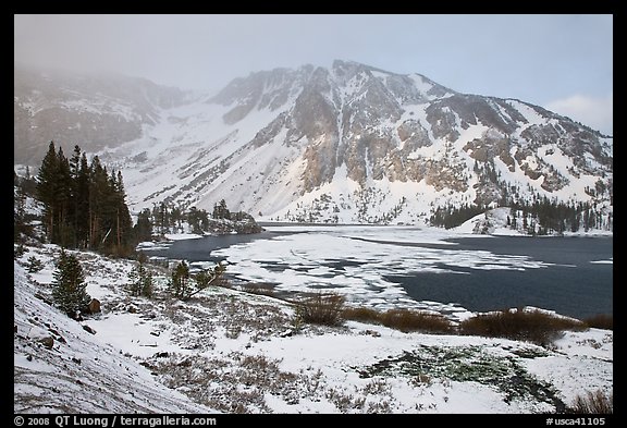 Partly frozen Ellery Lake and mountains with snow. California, USA