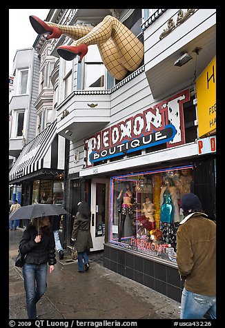 Woman passing with unbrella below giant legs. San Francisco, California, USA