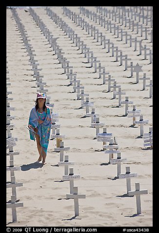 Girl wrapped in towel walking amongst crosses on beach. Santa Monica, Los Angeles, California, USA (color)