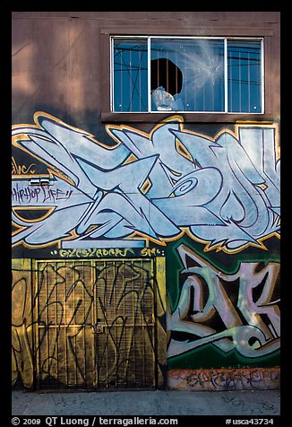 Mural paintings below broken window, Mission District. San Francisco, California, USA