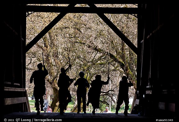 Silhouettes of dancers with sticks inside covered bridge, Felton. California, USA (color)