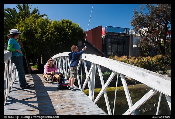 Boy fishing from arched bridge, Venice Canal Historic District. Venice, Los Angeles, California, USA (color)